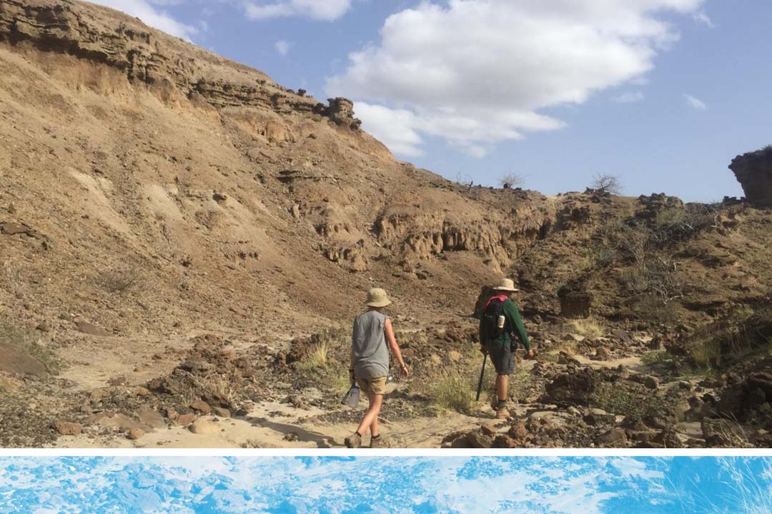 Two people trudging through a desertous field site