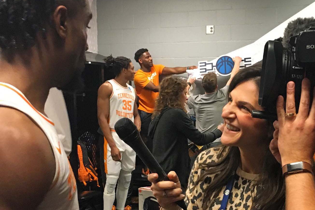 Danielle Santoro interviewing basketball player in a locker room.