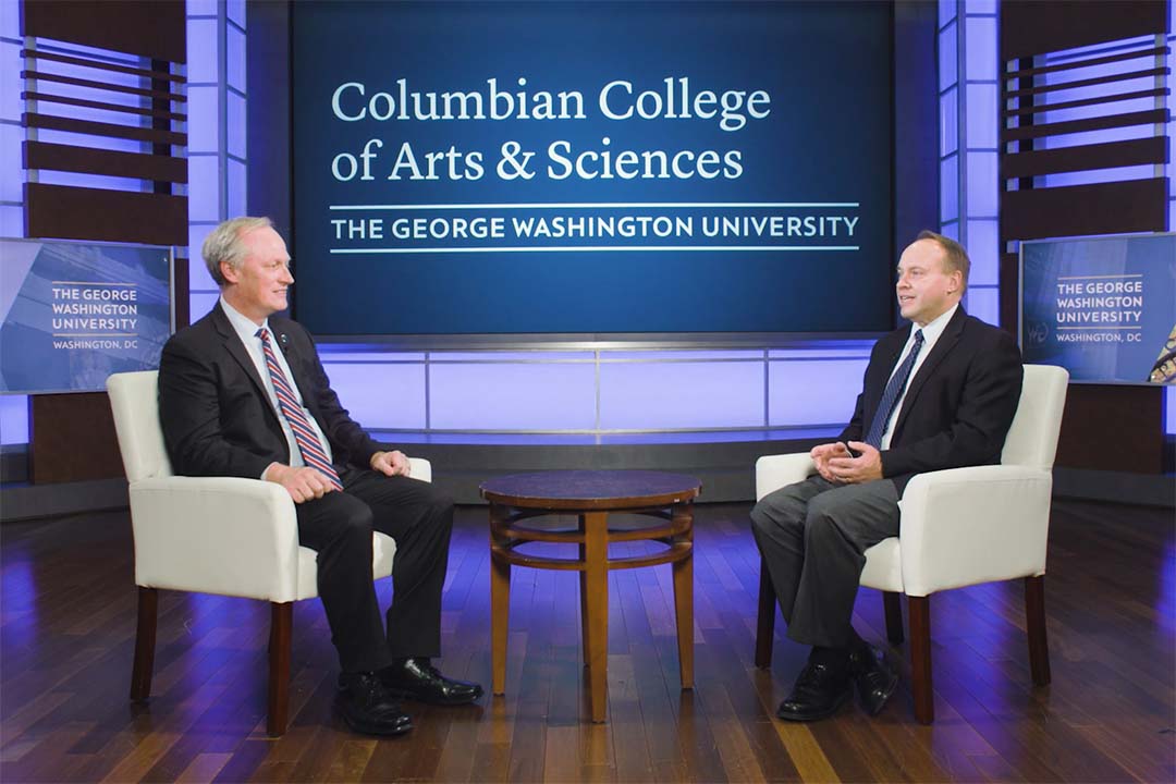 Denver Brunsman and Paul Wahlbeck talking on a stage with Columbian College of Arts and Sciences branding