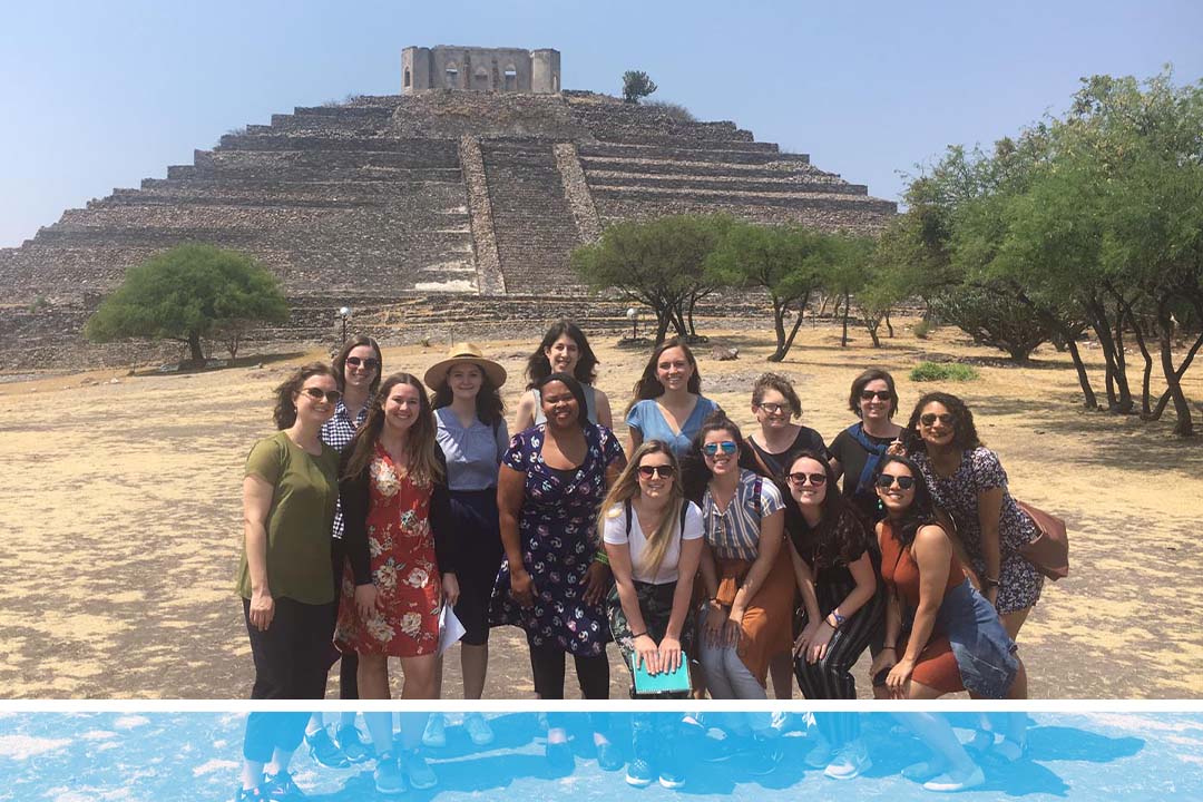 A group of GW students posing outside in front of a distant ancient building