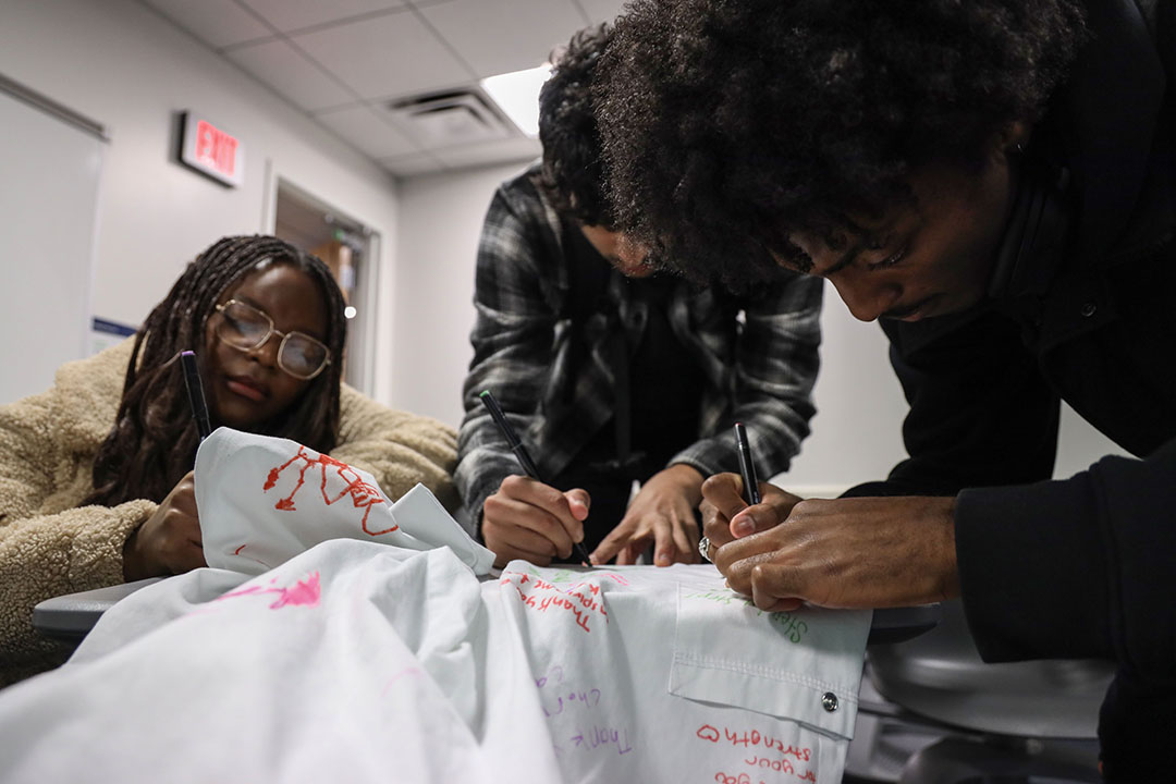 Following endurance athlete Kerry Gruson’s presentation to the Extreme Decisions class, from left, junior Bri Attey Mouanjo, senior Aahil Virani and junior Afure Moses-Taiga added well-wishes to her signature “performance pants.”  (Photos: Lily Speredelozzi)