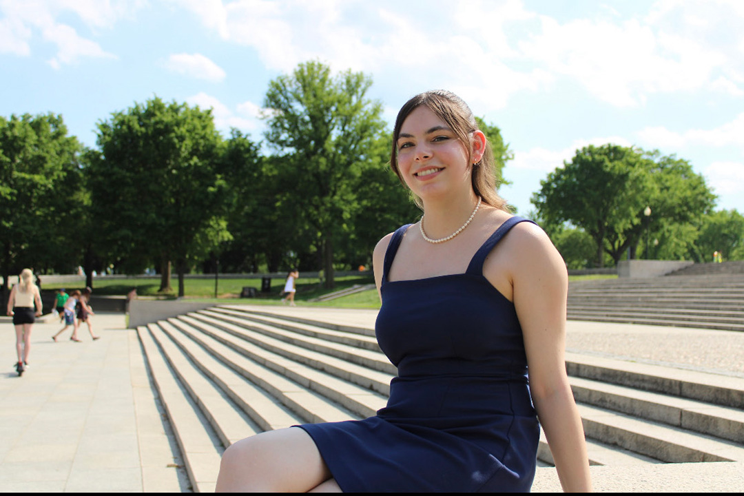 Emily Linder sitting on stone steps outside on a sunny day