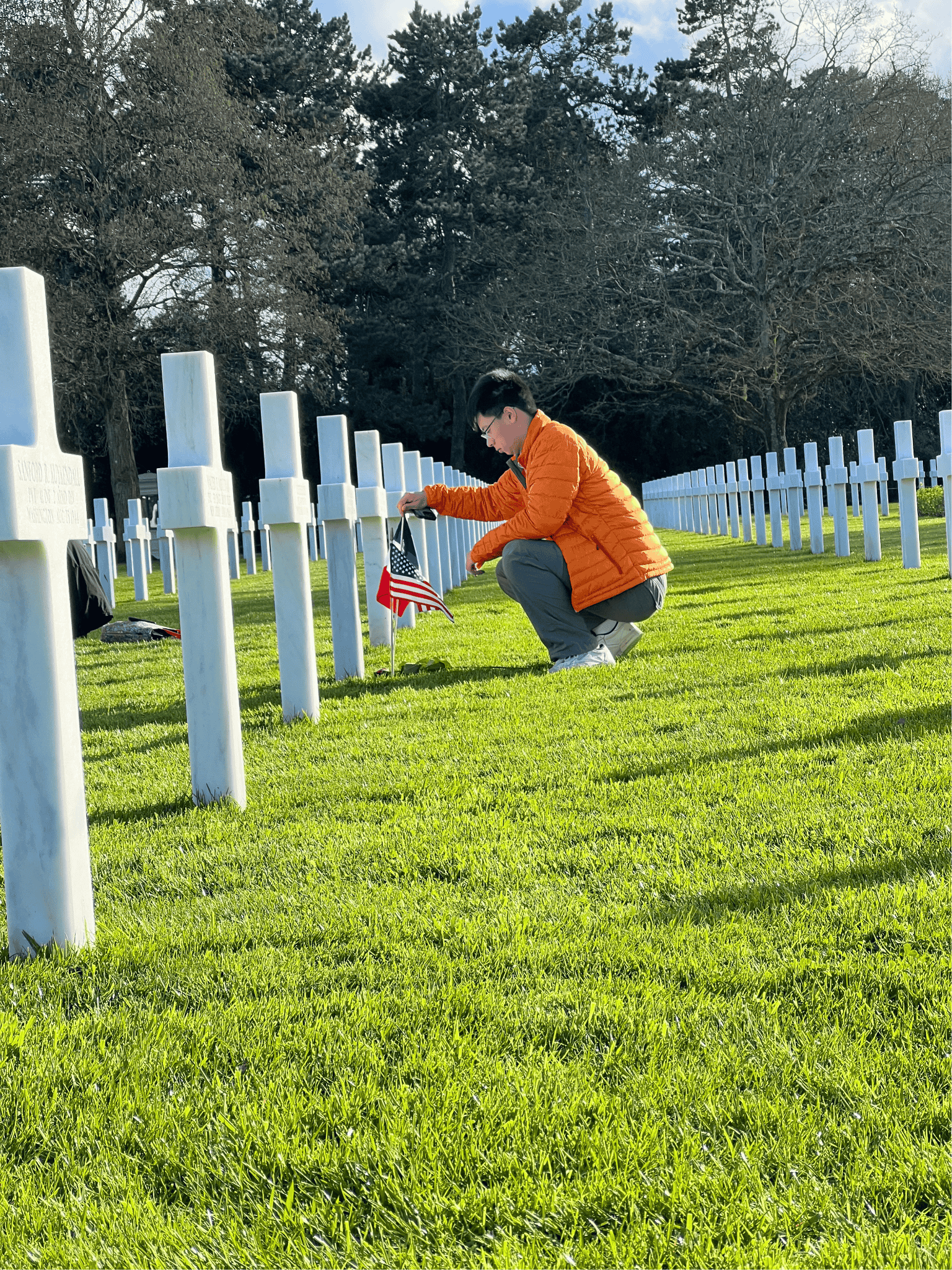 Student places flag at an American soldiers' gravesite in Normandy.