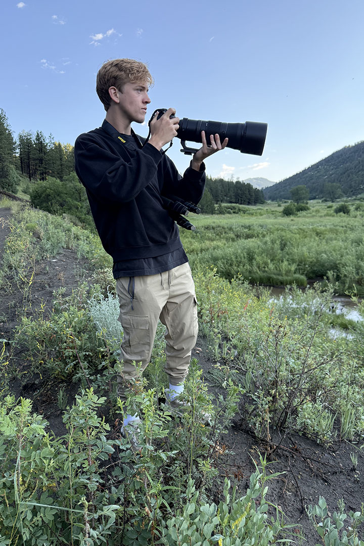 Andrew McCabe holding a camera in a grassy field