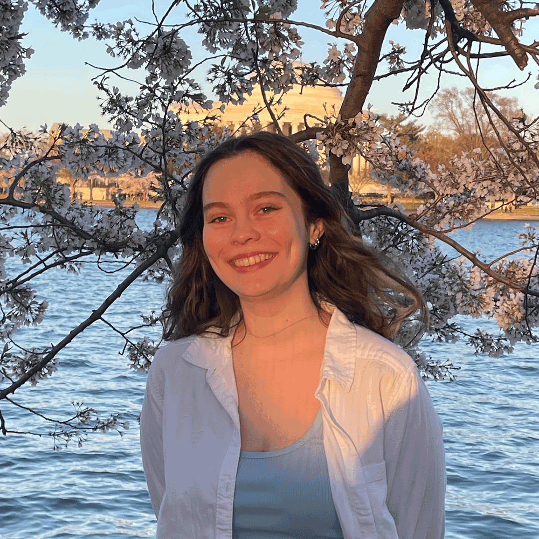 Kylie standing outside near the Jefferson memorial with cherry blossoms blooming