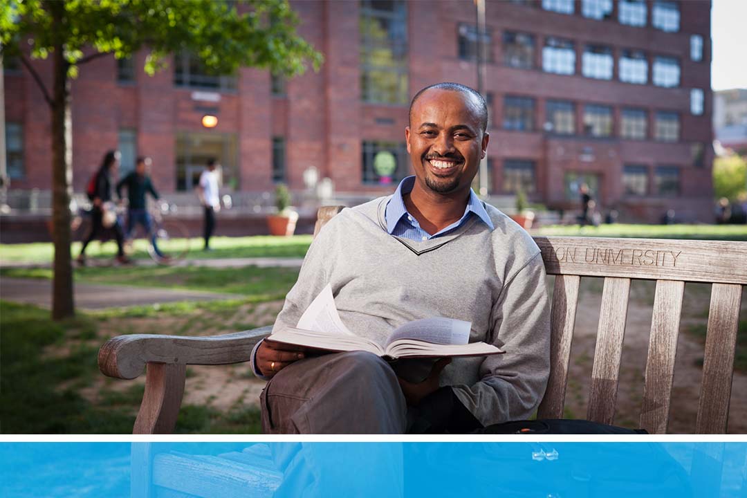 A smiling student on a GW bench outside