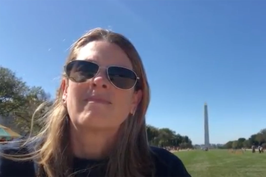 Lisa Benton-Short in sunglasses standing on the National Mall with the Washington Monument in the background