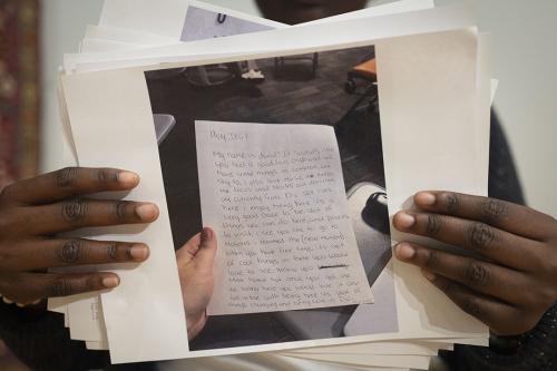 A person's hands holding a photograph of a handwritten letter, held in another pair of hands