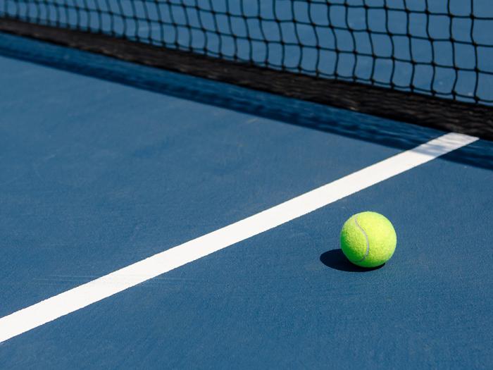 A tennis ball on a blue tennis court