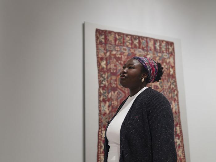 Inioluwa Jobi standing in front of a framed textile piece