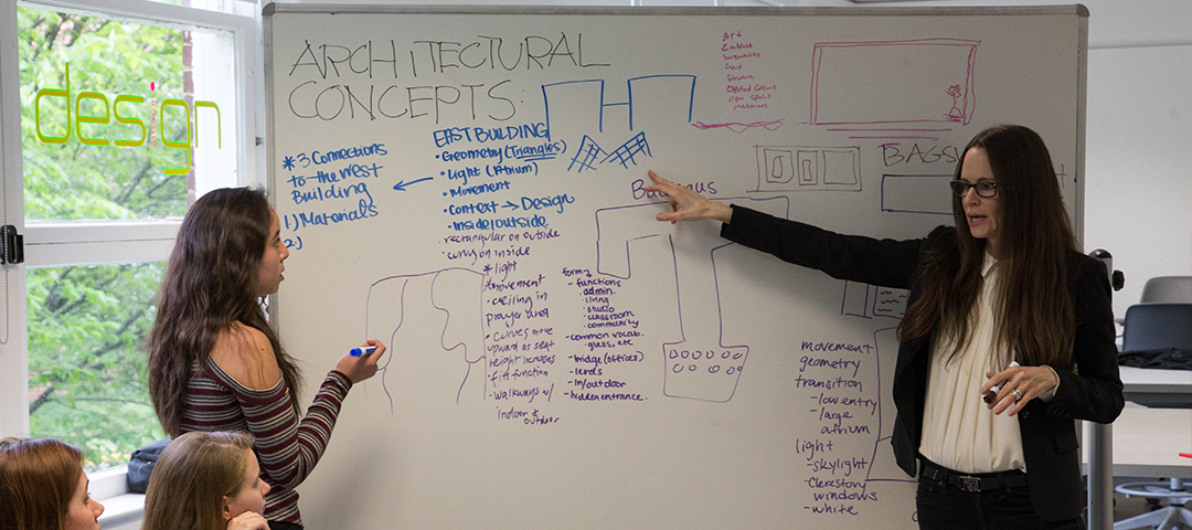 A professor and student standing in front of a whiteboard with architectural concepts on it