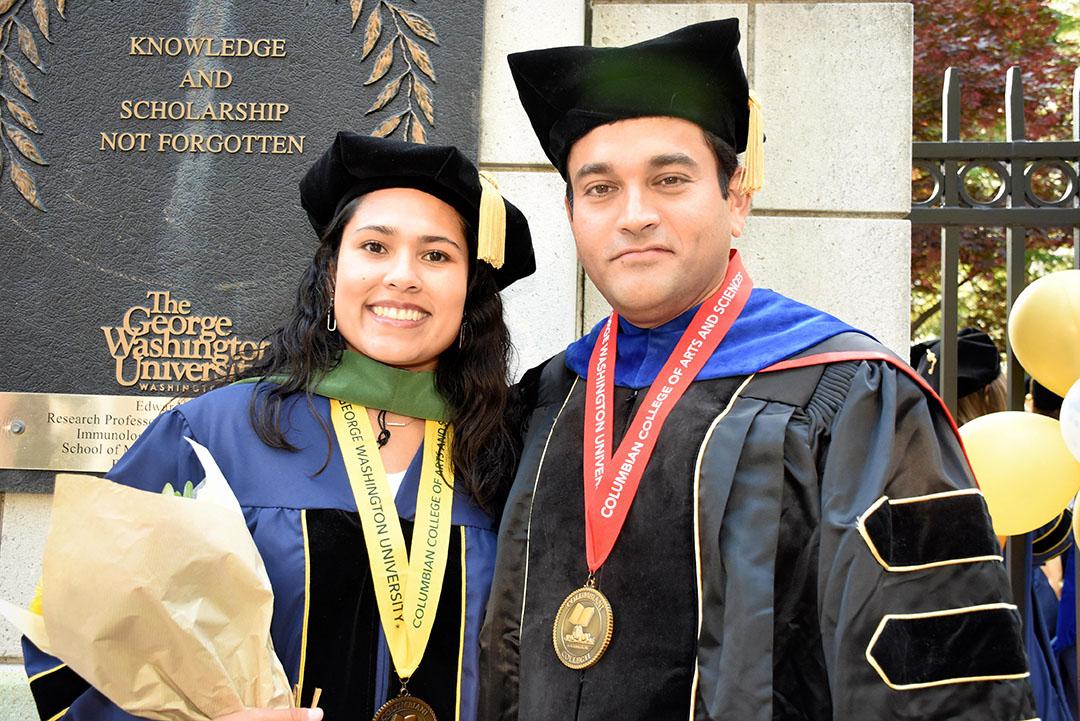 Two doctoral graduates holding flowers and smiling after the 2023 CCAS Doctoral Hooding Celebration