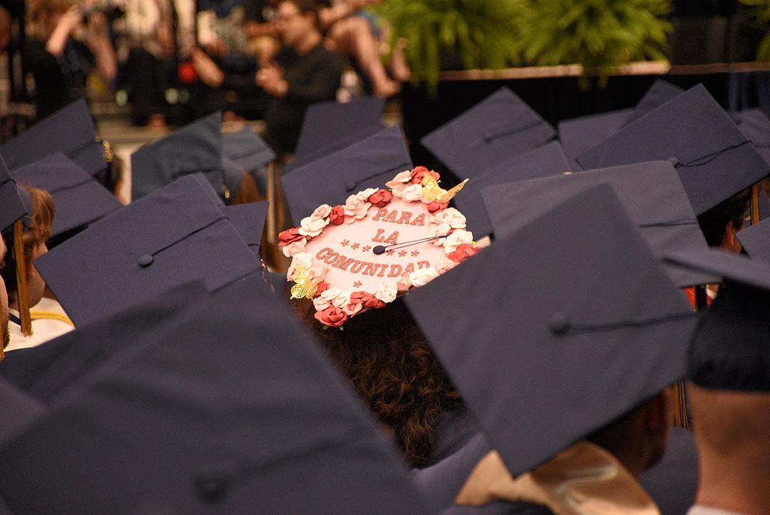 Graduation cap decorated with flowers and "Para La Comunidad"