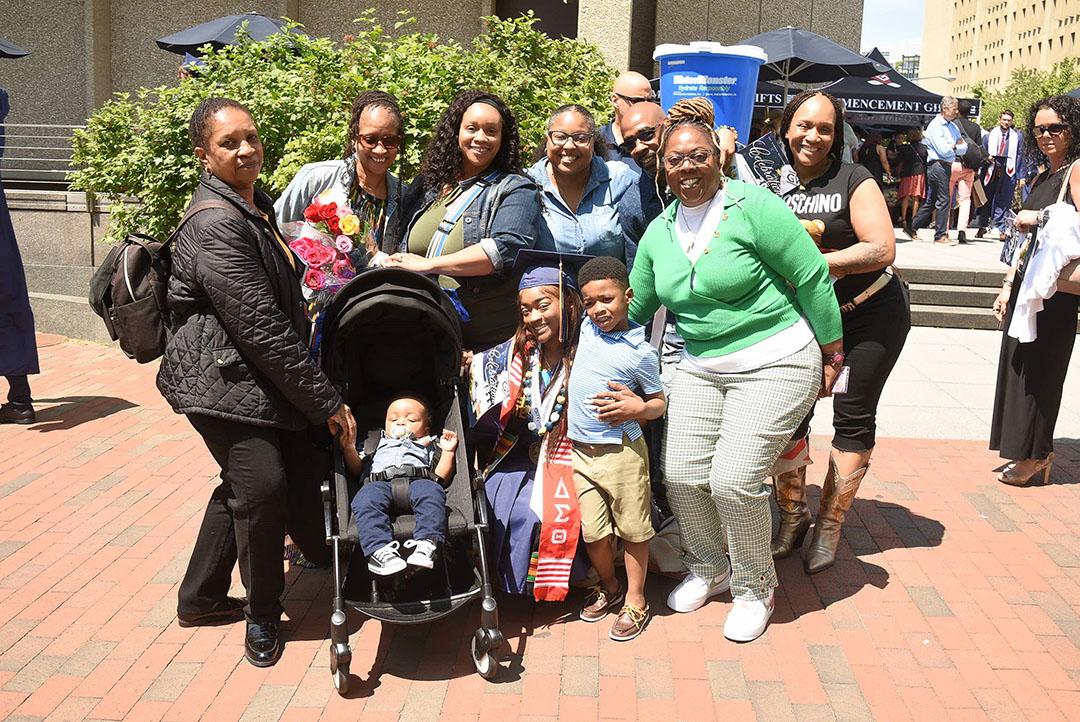 A large family stands with a new CCAS graduate outside