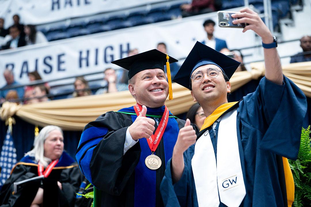 Dean Paul Wahlbeck smiling for a selfie with a master's graduate