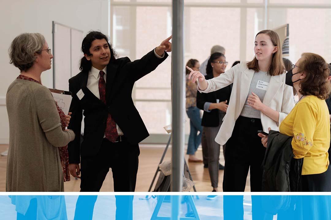 Students at the CCAS Research Showcase pointing to their presentation posters