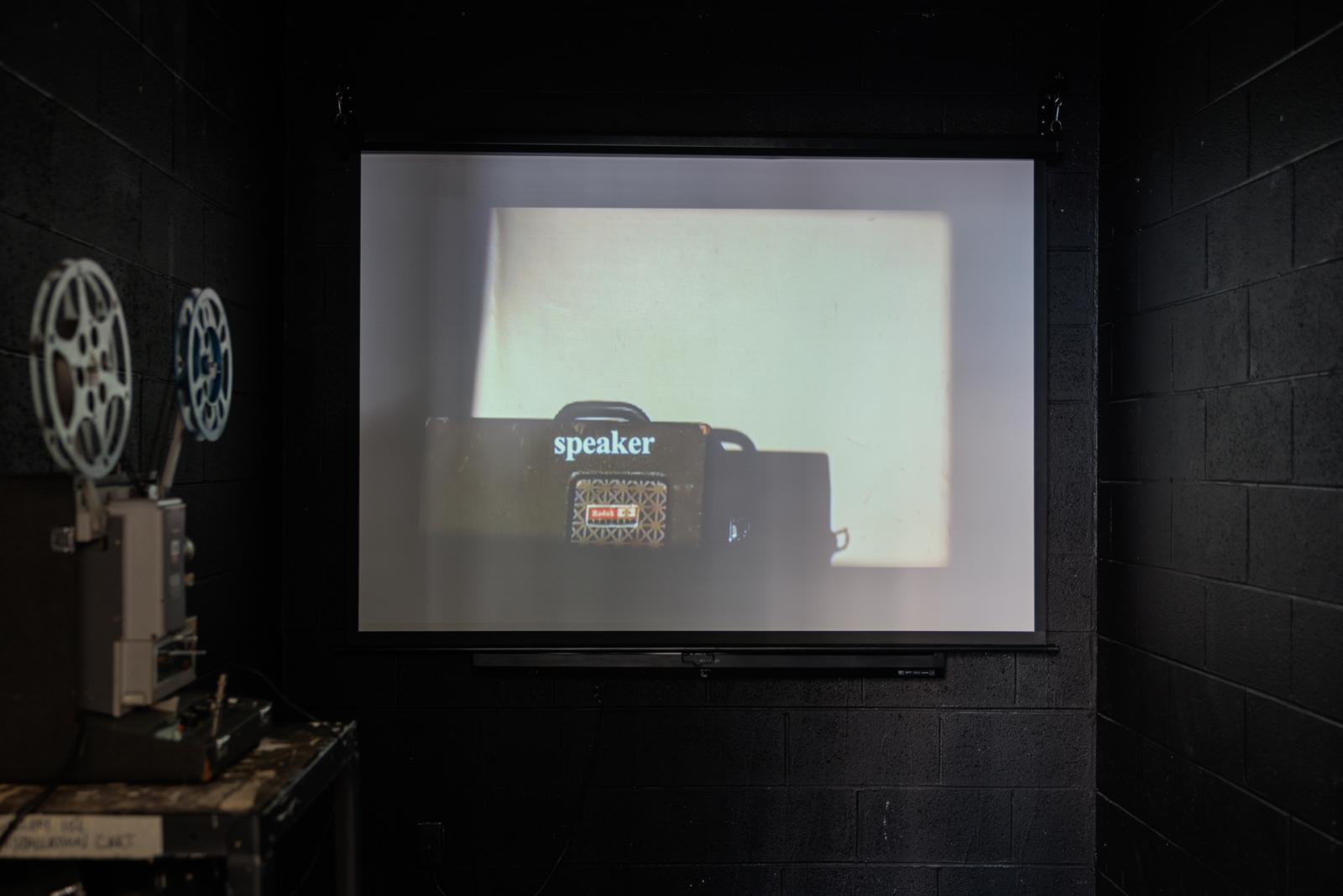 A projector displaying the word "speaker" on a wall