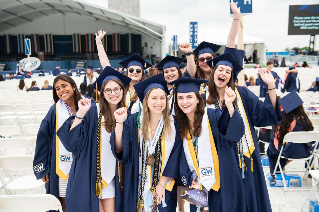 Recent graduates in caps and gowns cheering at the 2024 GW Commencement on the National Mall