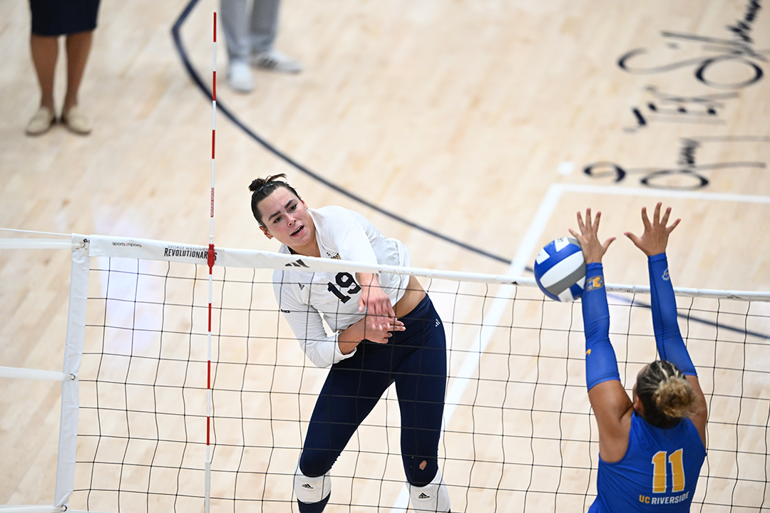 A woman hitting a volleyball over a net during a game