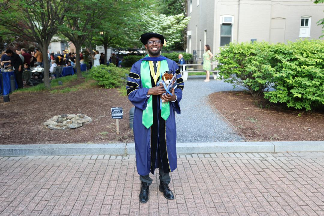 A CCAS GW graduate in cap and gown smiling at the 2025 commencement