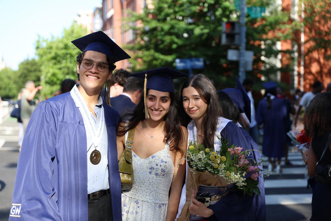Three undergraduate GW students at the 2025 Columbian College undergraduate ceremony wearing caps and gowns