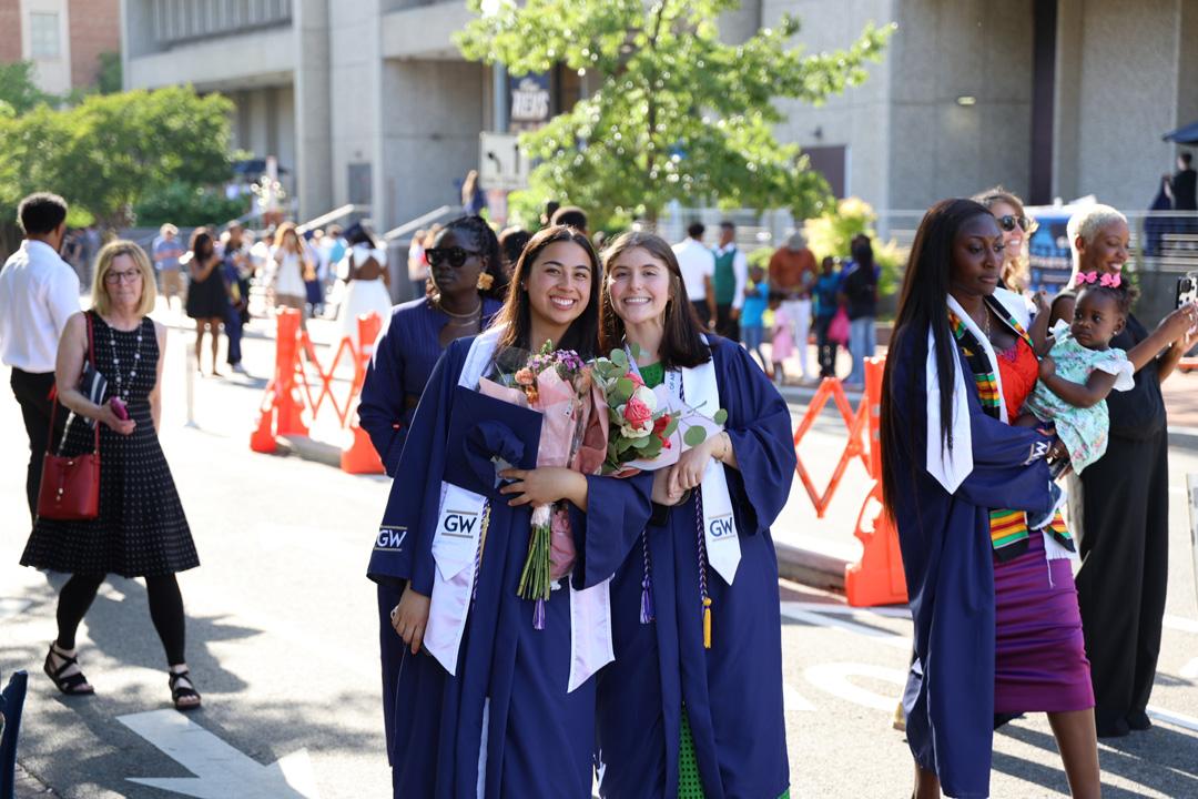CCAS undergraduate graduates in caps and gowns celebrating in Kogan Plaza