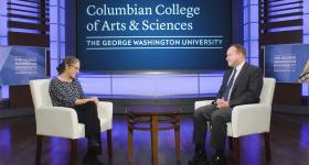 Sarah Binder and Paul Wahlbeck seated onstage talking in front of a Columbian College sign